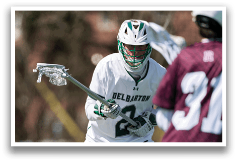 A man wearing a white uniform with the number 2 on it is holding a lacrosse stick. Description generated by AI
