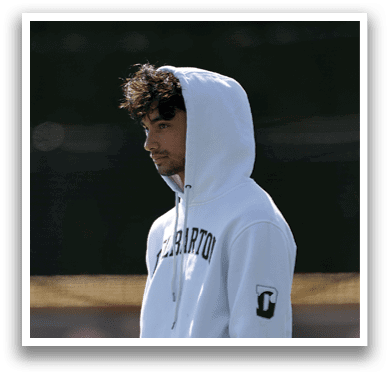 A man wearing a white hoodie with the word “Campbell" on it. Description generated by AI