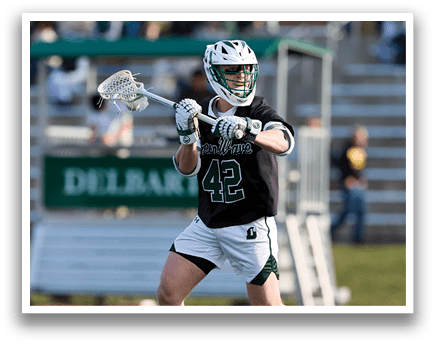 A man wearing a black shirt and white shorts is playing lacrosse. Description generated by AI