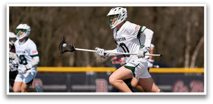 A man in a white and green uniform is running on a field. Description generated by AI