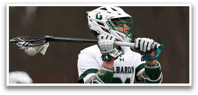 A man wearing a white and green shirt holding a lacrosse stick. Description generated by AI