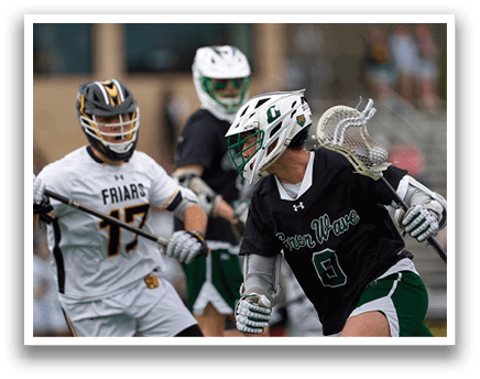 A man wearing a black shirt and white shorts is holding a lacrosse stick. Description generated by AI