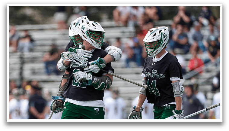 A group of men playing lacrosse on a field. Description generated by AI