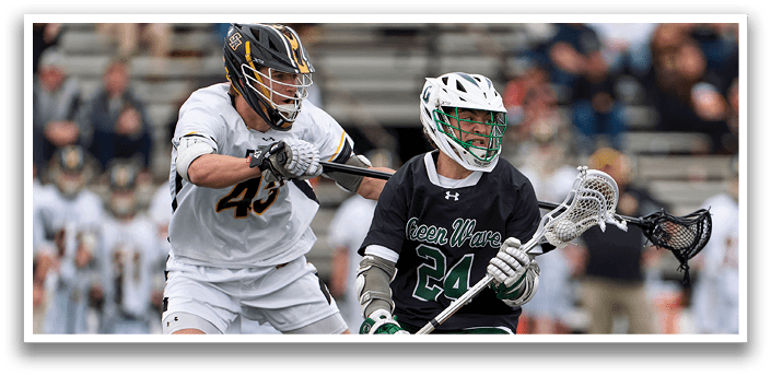 A man in a black shirt and green shorts is holding a lacrosse stick. Description generated by AI