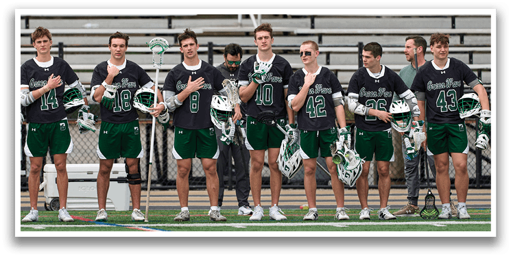 A group of lacrosse players standing on a field. Description generated by AI