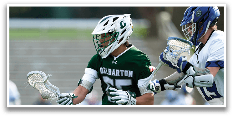 A man wearing a green shirt and white shorts holding a lacrosse stick. Description generated by AI