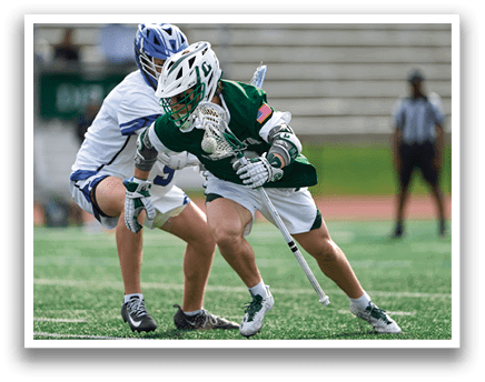 Two men playing lacrosse on a field. Description generated by AI