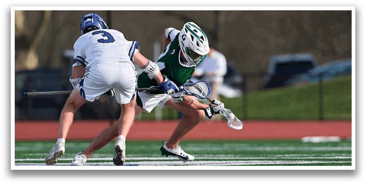Two men playing lacrosse on a field. Description generated by AI