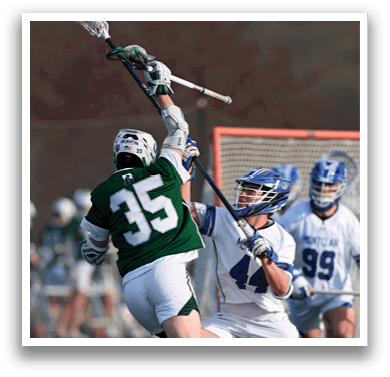 A man in a green shirt and white shorts is holding a lacrosse stick. Description generated by AI
