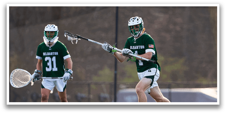 A man in a green and white uniform is running with a lacrosse stick. Description generated by AI