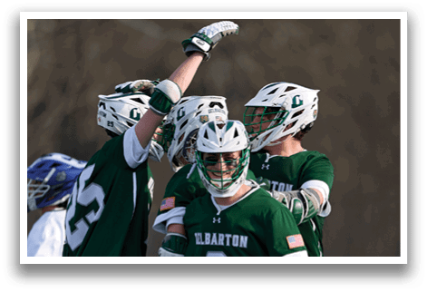 A group of men wearing green jerseys and white shorts are celebrating a goal. Description generated by AI