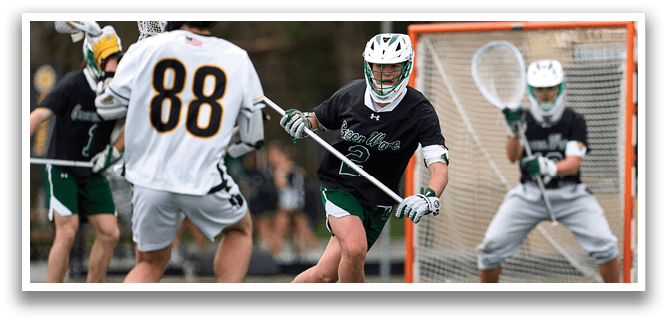 A man in a black shirt and green shorts is holding a lacrosse stick. Description generated by AI