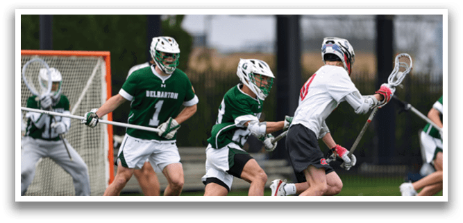 A group of men playing lacrosse on a field. Description generated by AI