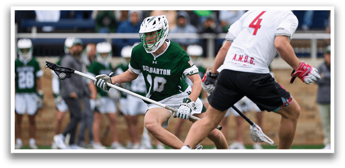 A man in a green and white uniform is holding a stick and running on a field. Description generated by AI