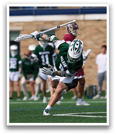 A man in a green and white uniform is holding a lacrosse stick. Description generated by AI