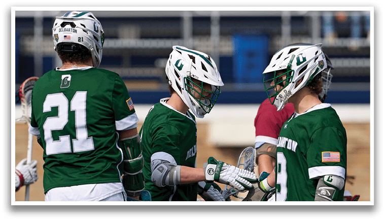A group of men wearing green shirts and white shorts playing lacrosse. Description generated by AI