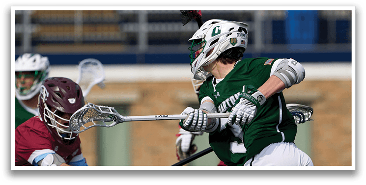 A man in a green jersey is running with a stick. Description generated by AI