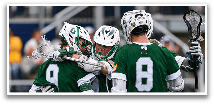 Three men wearing green shirts and white shorts are hugging each other on a field. Description generated by AI