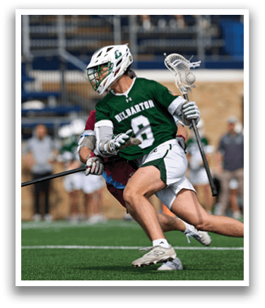 A man in a green and white uniform is running with a lacrosse stick. Description generated by AI