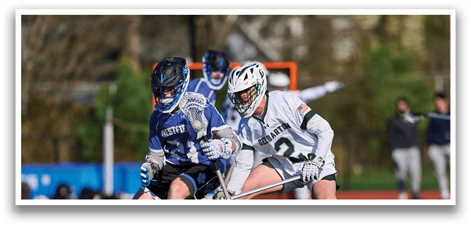 Two men playing lacrosse on a field. Description generated by AI