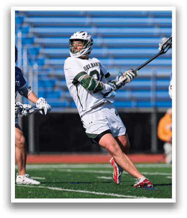 A man in a white jersey is holding a lacrosse stick. Description generated by AI