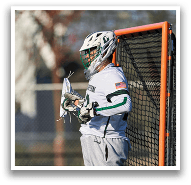 A man wearing a white and green uniform is standing in front of a net. Description generated by AI