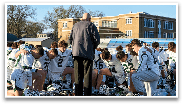 A group of people wearing white jerseys are kneeling on the ground. Description generated by AI
