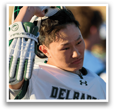 A man wearing a white jersey with the word Delaware on it. Description generated by AI