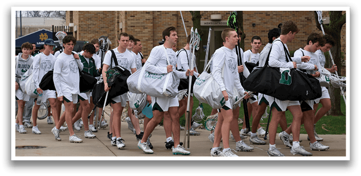 A group of people walking down a sidewalk with their lacrosse sticks. Description generated by AI