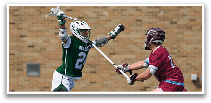 A man in a green jersey is holding a lacrosse stick. Description generated by AI