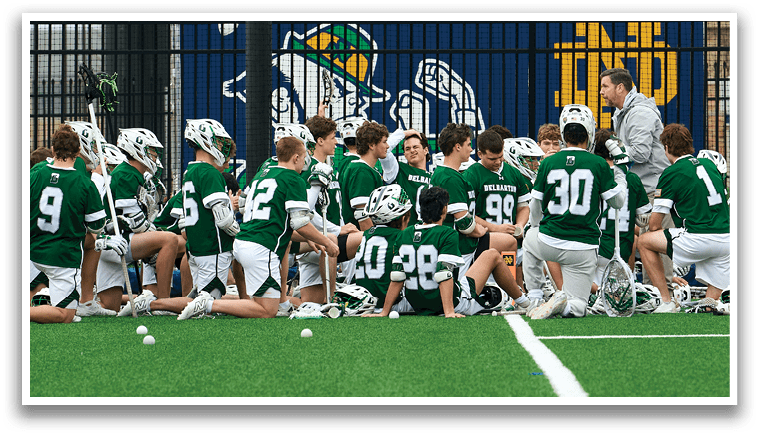 A group of people wearing green shirts and white shorts are sitting on a field. Description generated by AI