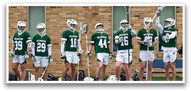 A group of men wearing green and white uniforms are standing on a field. Description generated by AI