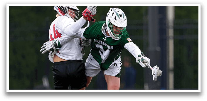 Two men playing lacrosse on a field. Description generated by AI