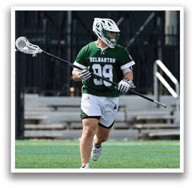 A man wearing a green and white jersey is holding a lacrosse stick. Description generated by AI