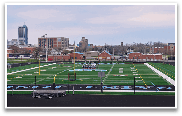 A football field with a group of people on it. Description generated by AI
