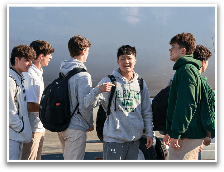 A group of people wearing green and white uniforms and holding lacrosse sticks. Description generated by AI