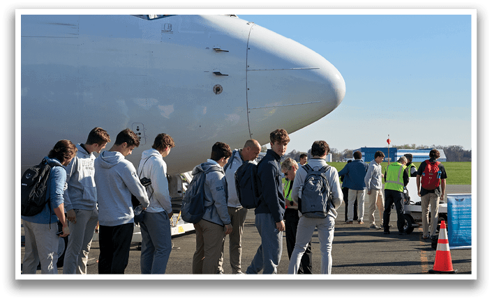 A group of people are lined up to board a plane. Description generated by AI