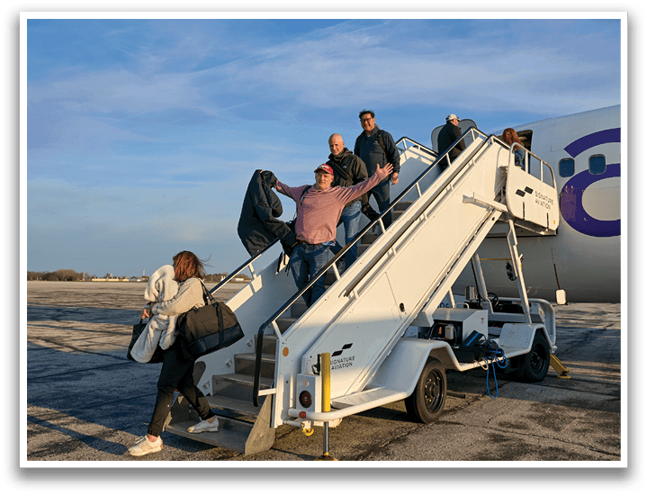 A group of people are getting off a plane. Description generated by AI