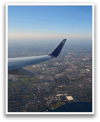 A plane wing with a blue tail. Description generated by AI