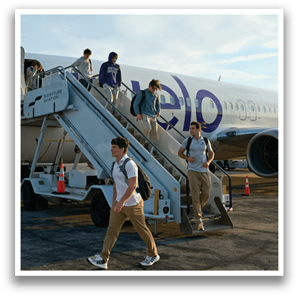 A group of people are walking up a ramp to a plane. Description generated by AI