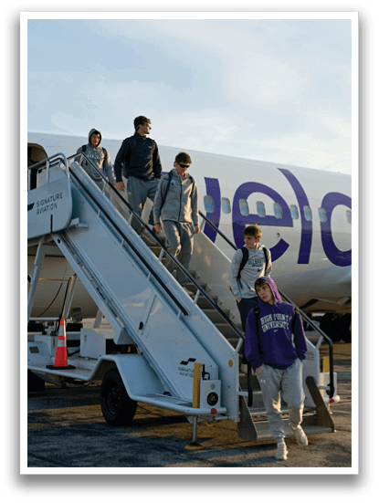 A white airplane with a purple logo on the side. Description generated by AI