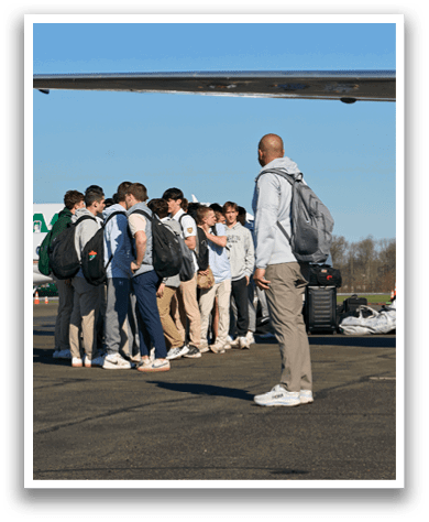 A group of people standing on an airport tarmac. Description generated by AI