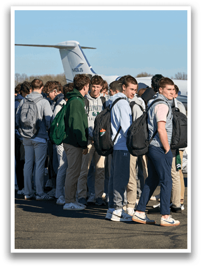 A group of people standing on the tarmac in front of a white airplane. Description generated by AI