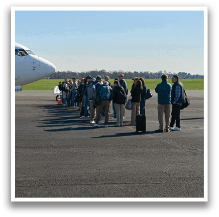 A group of people are standing in front of a white airplane. Description generated by AI