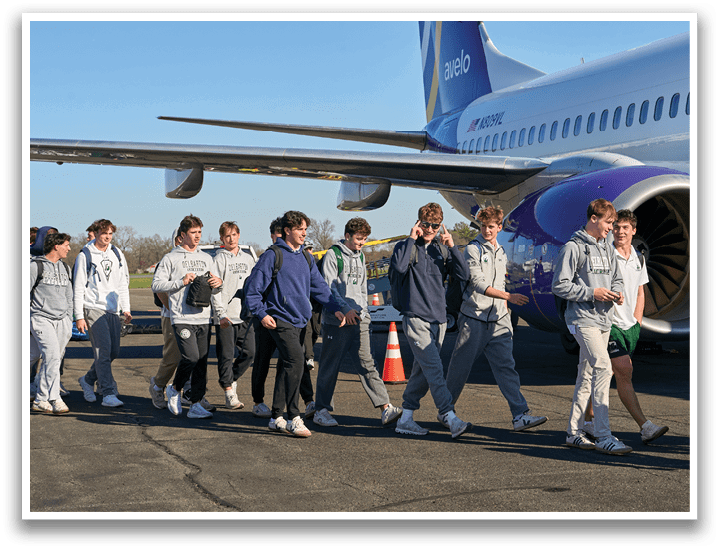 A group of people wearing green and white uniforms and holding lacrosse sticks. Description generated by AI