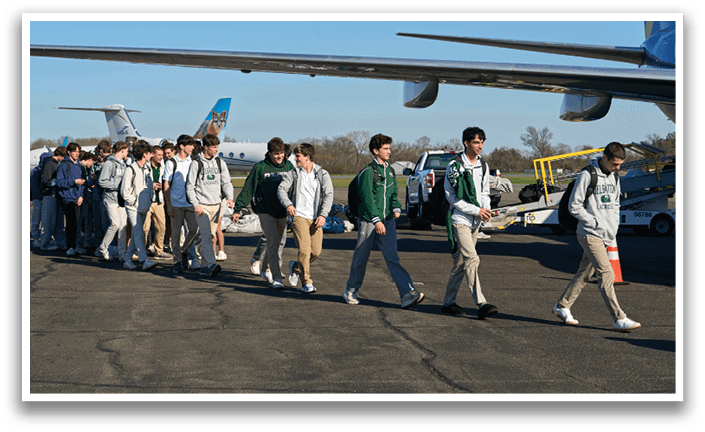 A group of people walking on a tarmac. Description generated by AI