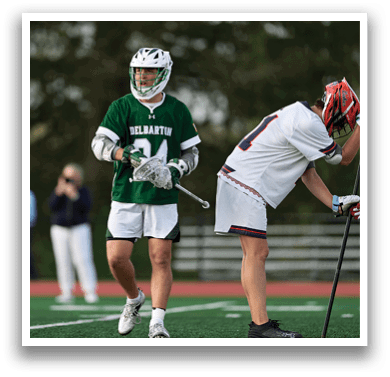 A man in a green jersey is holding a stick. Description generated by AI