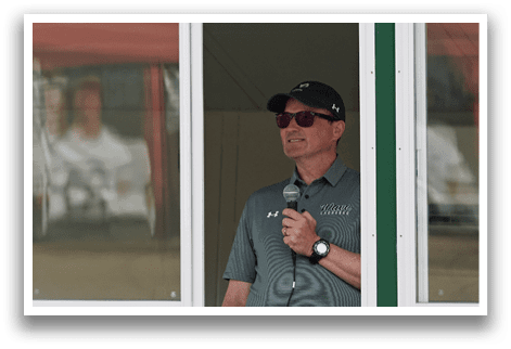 A man wearing sunglasses and a black hat is standing in front of a window. Description generated by AI