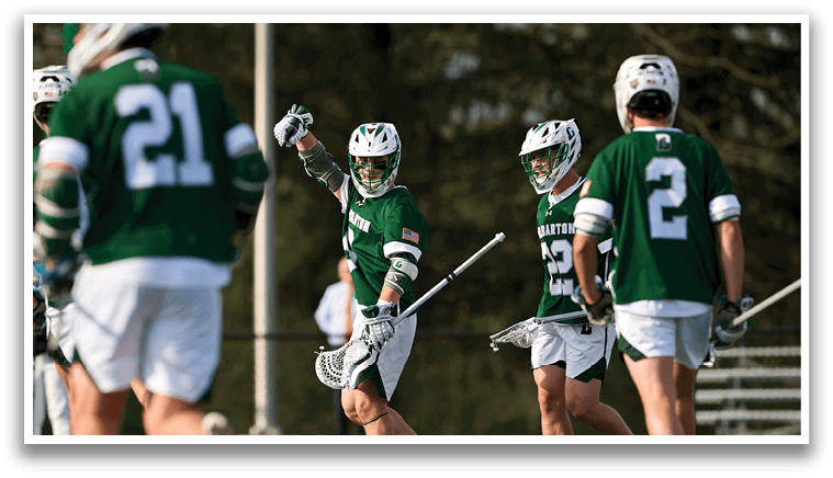 A group of men playing a game of lacrosse on a field. Description generated by AI