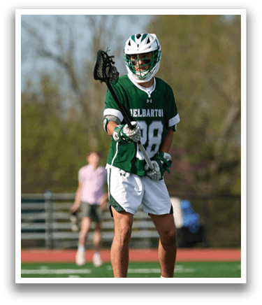 A man in a green and white uniform holding a lacrosse stick. Description generated by AI